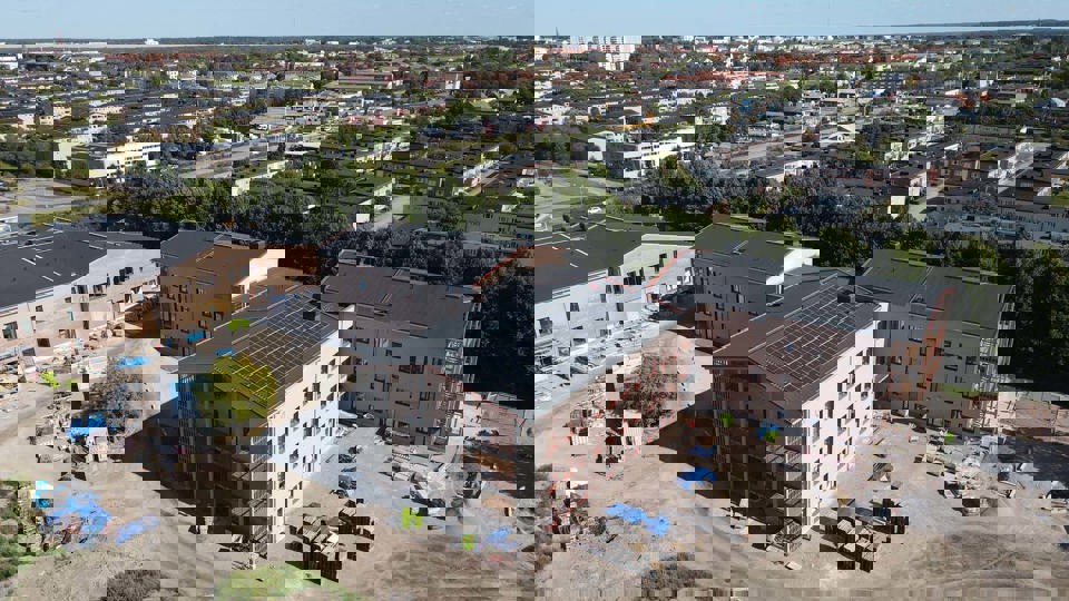Flygfoto över byggplats där en skola växer fram.