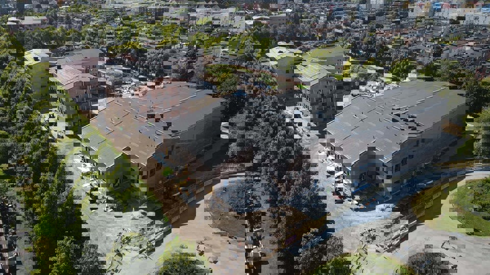 Flygfoto över byggplats där skola med skolgård och gröna träd växer fram.