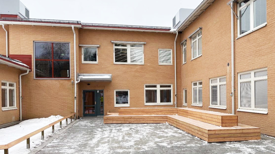 Nyrenoverad skolentré med bänkar i förgrund.