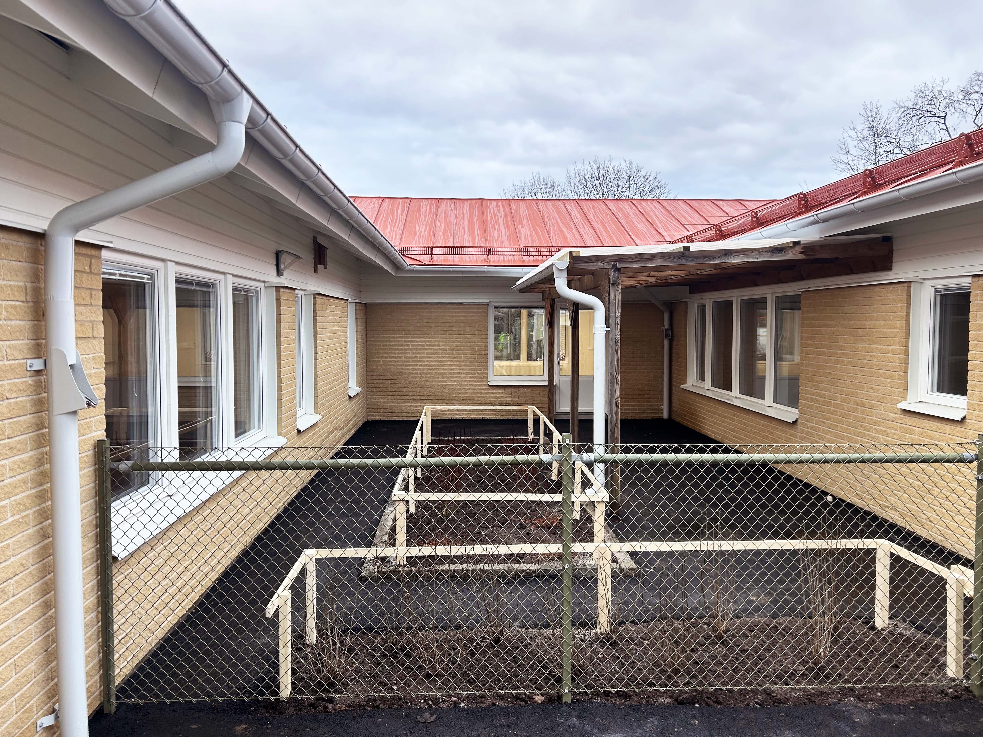 Nyrenoverad förskolebyggnad i tegel med nyplantering i förgrunden.