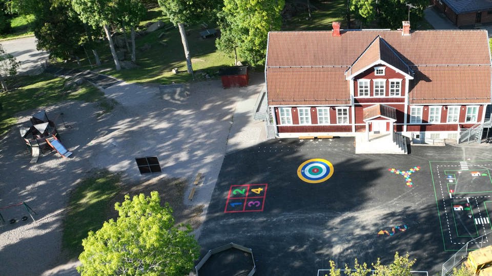 Flygvy över nyrenoverad skolgård, med asfaltsmålningar i färg.