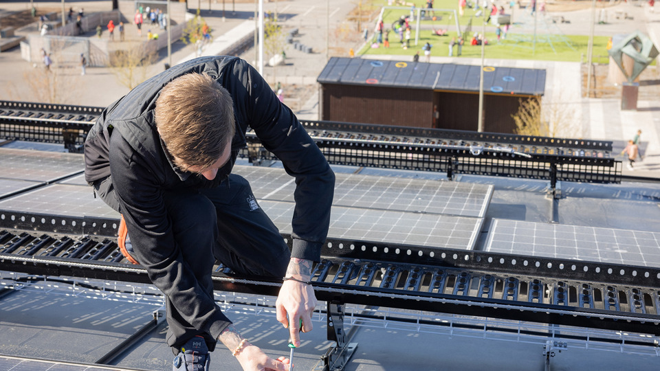 Drifttekniker skruvar på en solcellsanläggning