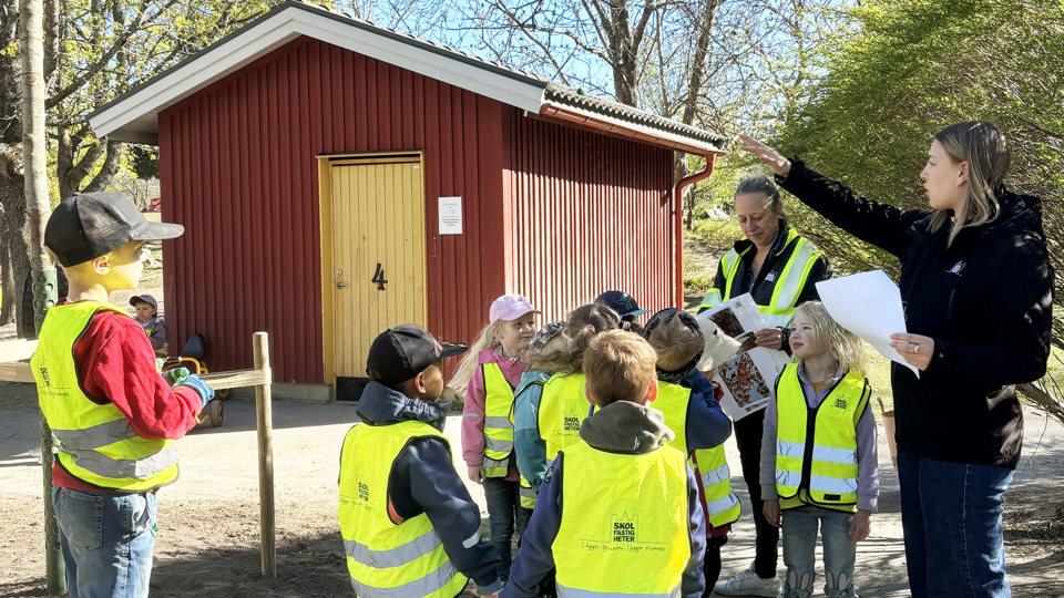 En grupp barn med gula västar står på en förskolegård.