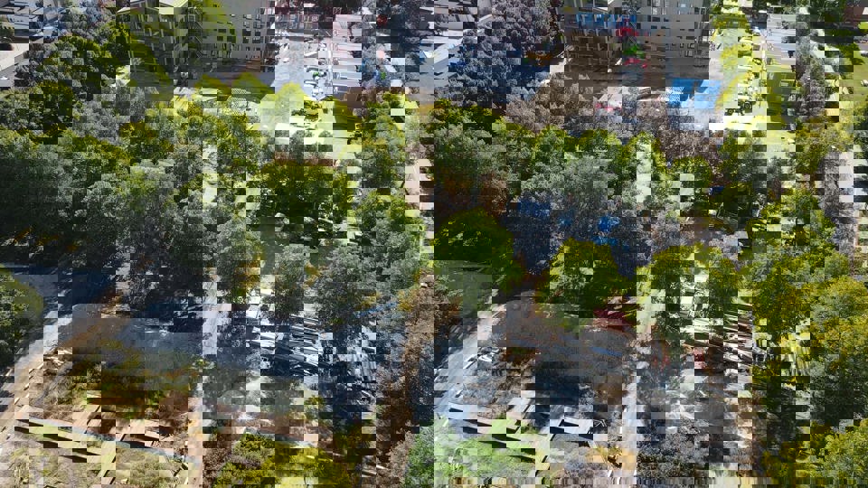 Flygfoto över byggplats där skola med skolgård och gröna träd växer fram .