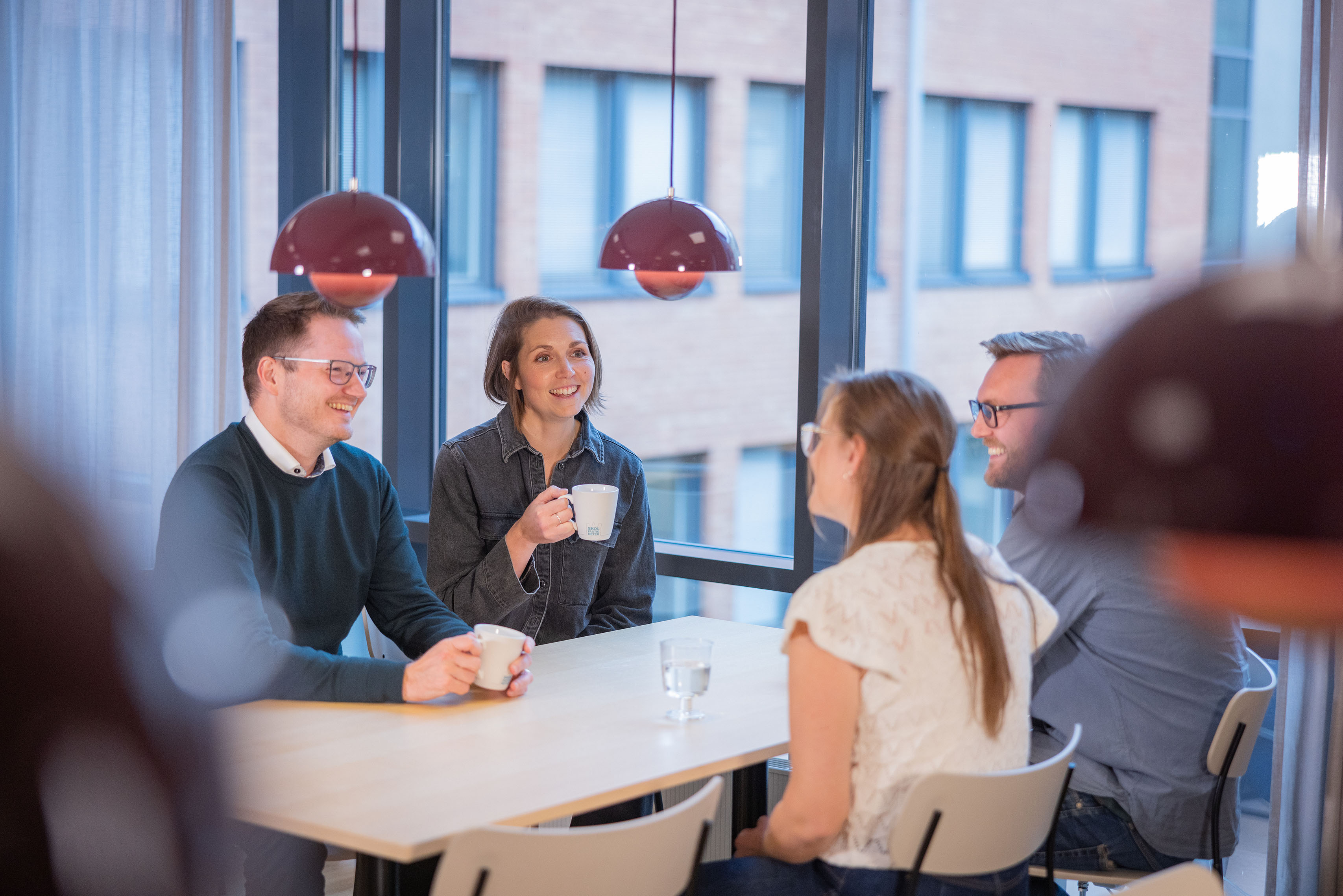 Fyra kollegor som sitter och fikar vid ett köksbord