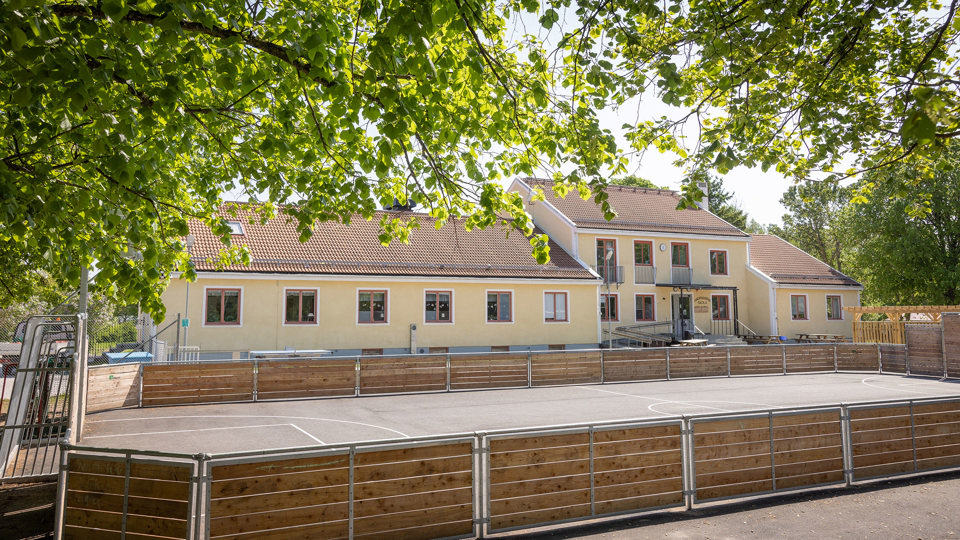 Gul skola med fotbollsplan i förgrunden